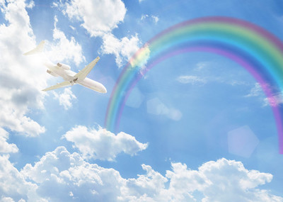 湛蓝色的云彩和彩虹上空飞行的飞机