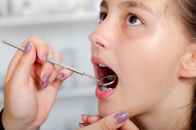 小女孩张大嘴宽在治疗她的牙齿的牙医的特写镜头