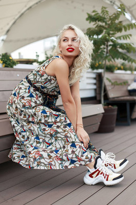 酷时尚漂亮的模特女士穿着时髦的复古服装, 穿着时尚鞋坐在木凳上.