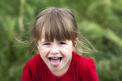 微笑的小女孩显示的舌头.年轻可爱的小女孩 gesturi